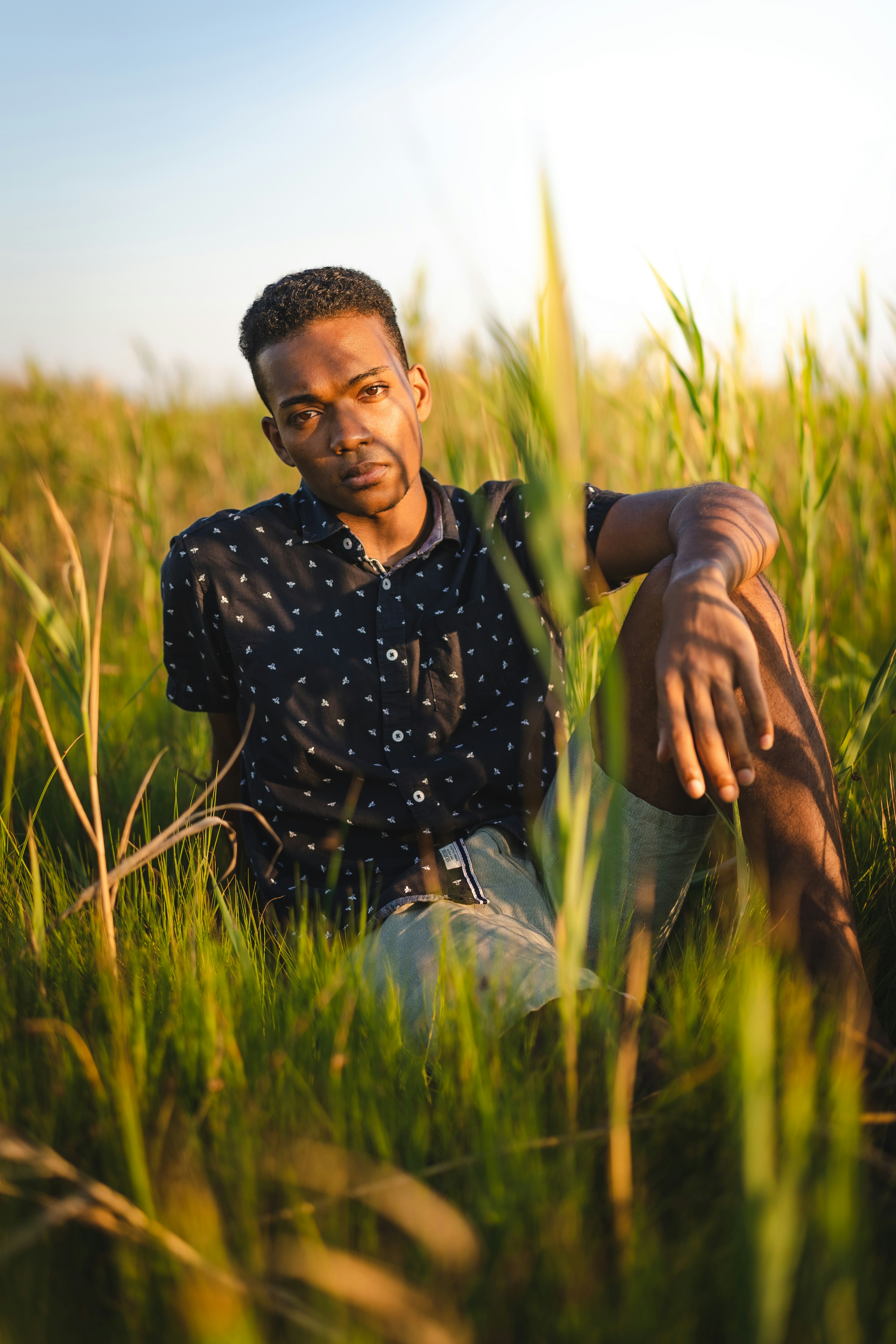 man in black and white polka dot dress shirt sitting on green grass field